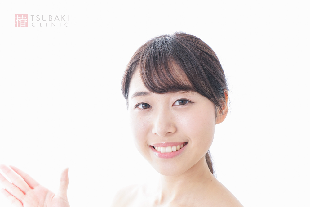 明るい背景で笑顔を見せる女性の写真。エラボトックスやハイフ施術後のイメージとして使われるビジュアル